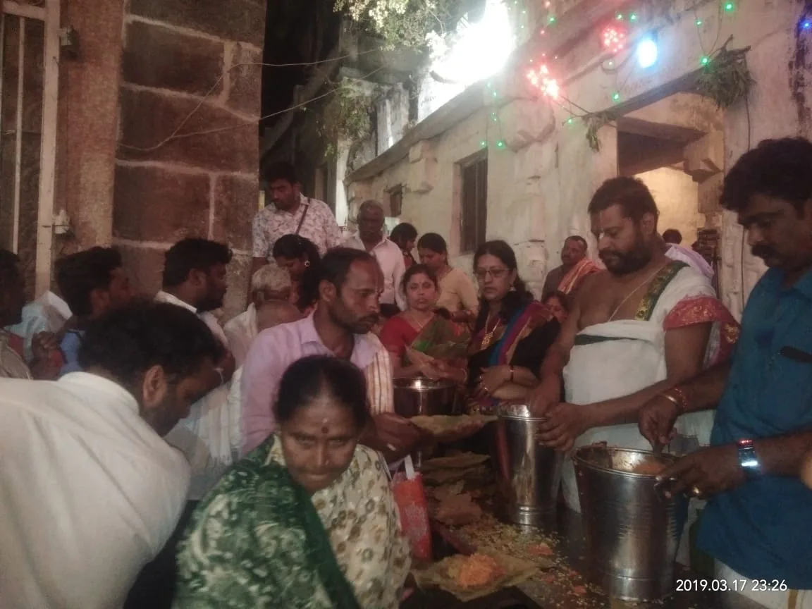 Rice and curry ladled from steel buckets onto leaf plates in a lane strung with coloured lights, the queue pressing in on both sides of the servers late at night
