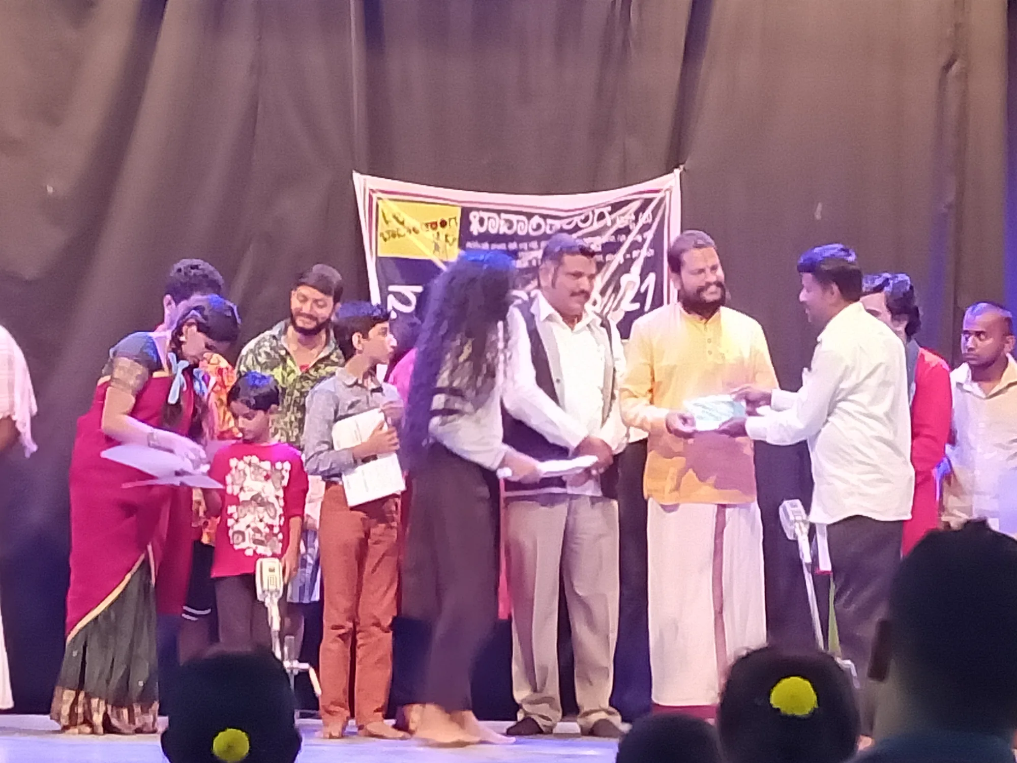 Children and their parents lined across a stage receiving prize packets from the organisers under the event's banner