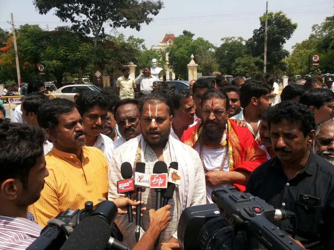 A crowd of press microphones and cameras held out to two men speaking on a road outside a public building