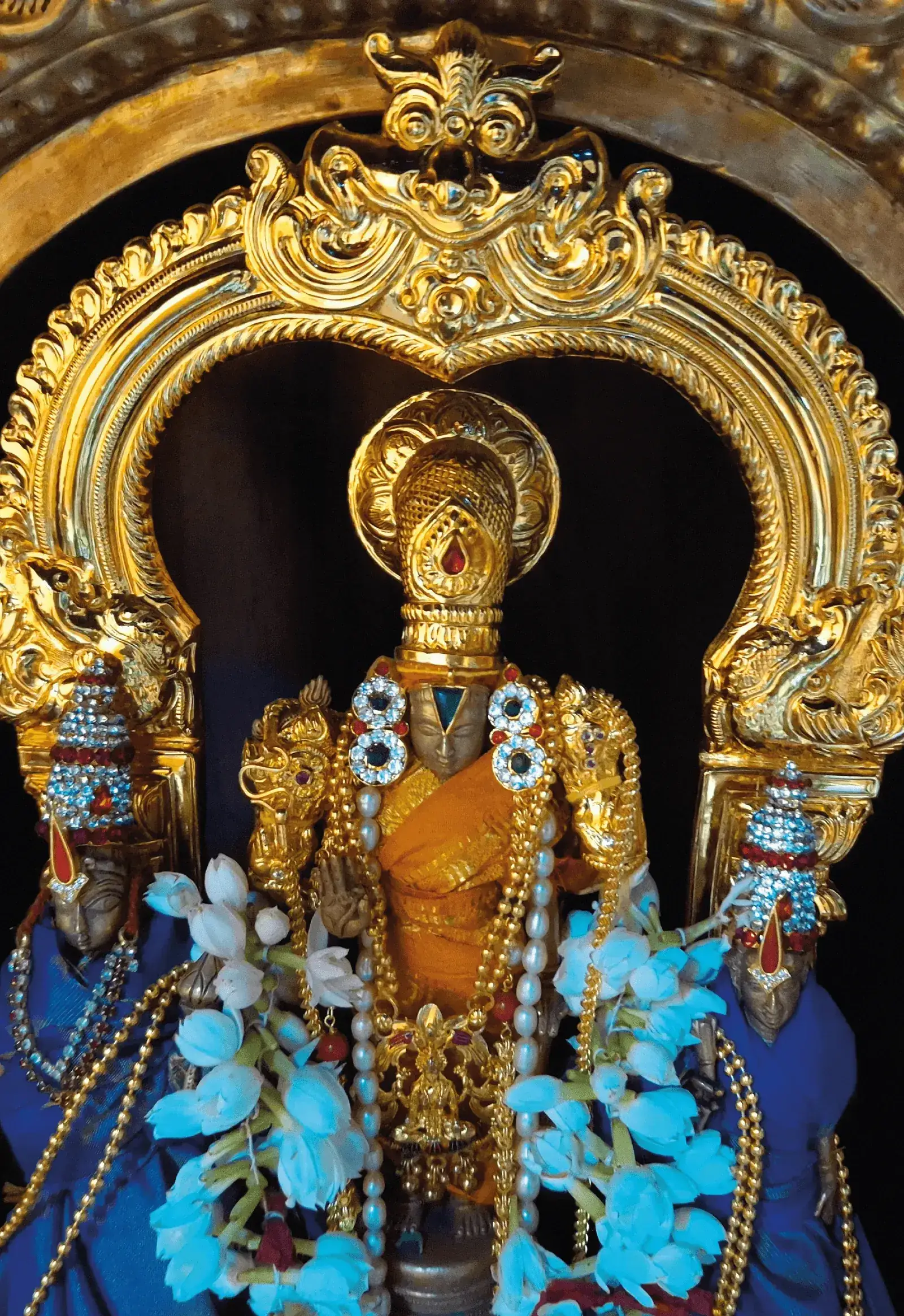 The utsava murti of Sri Cheluvanarayana Swamy adorned in gold ornaments and blue lotus garlands