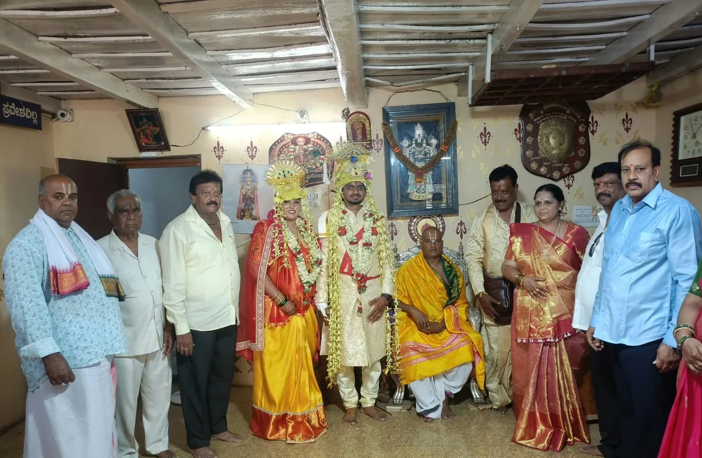 A bride and groom still in their wedding silks and garlands standing with both families before the mandira shrine, having come for a blessing on the day