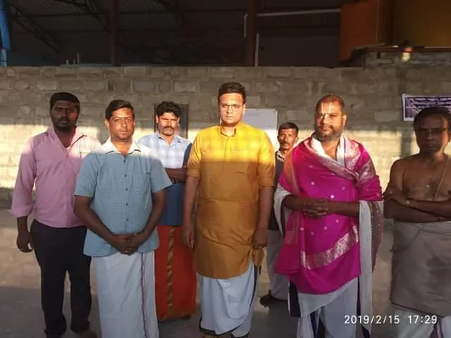Sri Yaduveer Wadiyar in a gold kurta standing with Guruji, who wears a magenta shawl, and the men of the trust in the hall of the kshetra